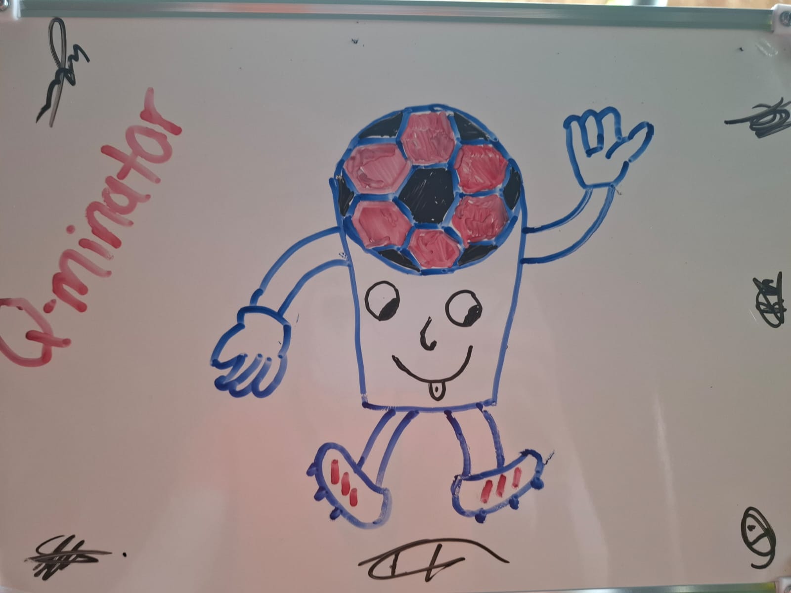 Child's marker drawing of a waving soccer-ball-headed mascot with a cup-shaped body